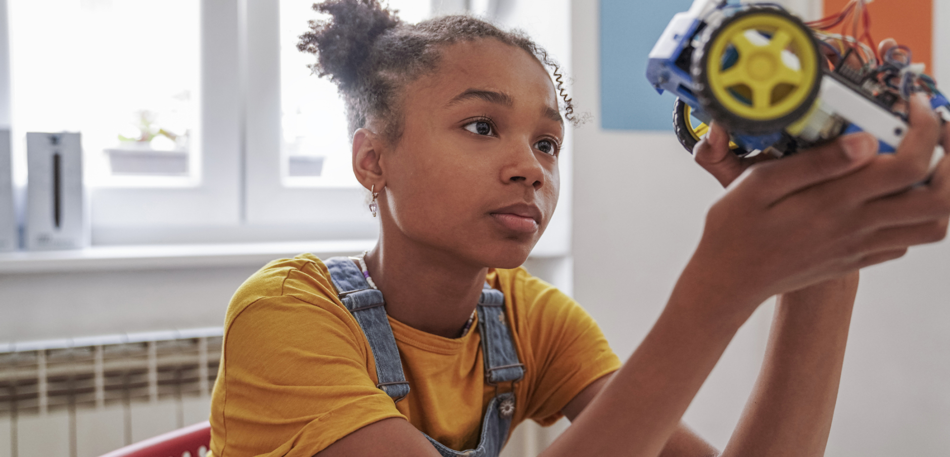 Young girl holding a robot and looking at the machinery